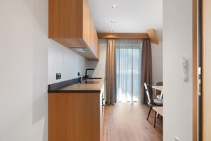A modern kitchen with wooden cabinetry, a built-in stove, and a dining area with a table and chairs. - Goldener Adler Apartment Family Plus 9 with Balcony, Sauna & Breakfast Included, New 2026 (Trodena nel Parco naturale)