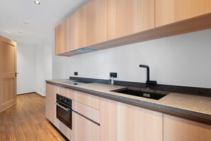 A modern kitchen with wooden cabinets, a granite countertop, a double sink, and built-in appliances. - Goldener Adler Apartment Family Plus 9 with Balcony, Sauna & Breakfast Included, New 2026 (Trodena nel Parco naturale)