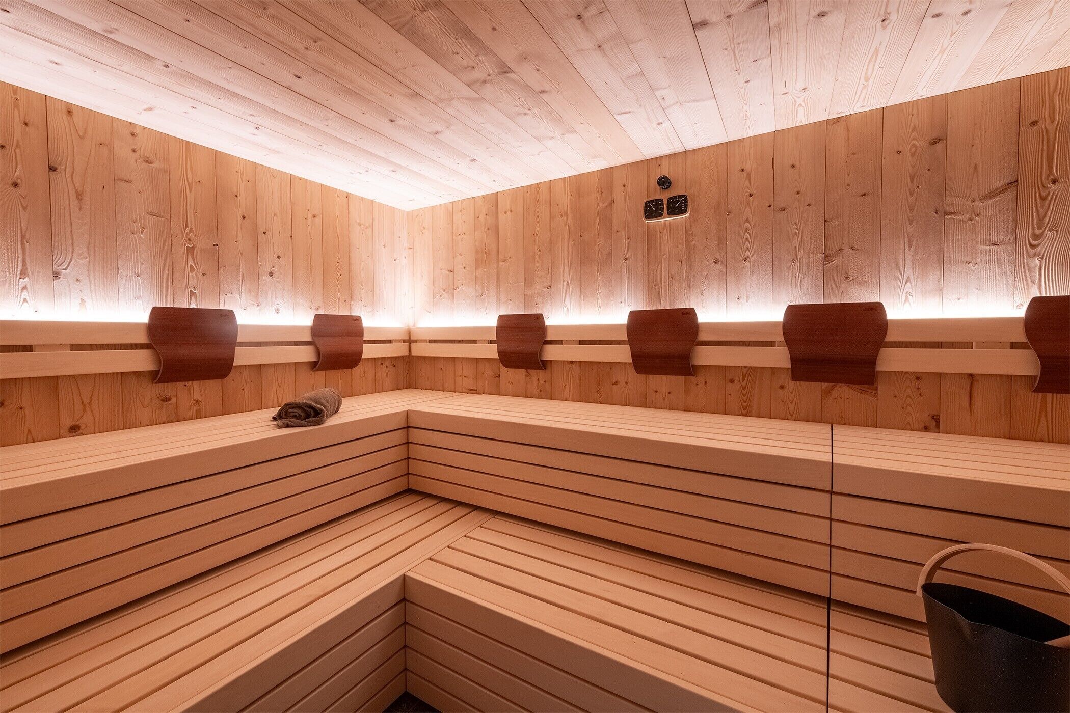 A sauna with wooden benches and a sloped floor design.