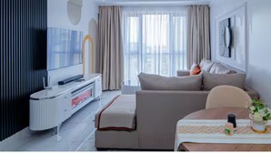 Ein modernes Wohnzimmer mit Sofa, Fernseher und einem Essbereich mit Tisch und Stühlen.