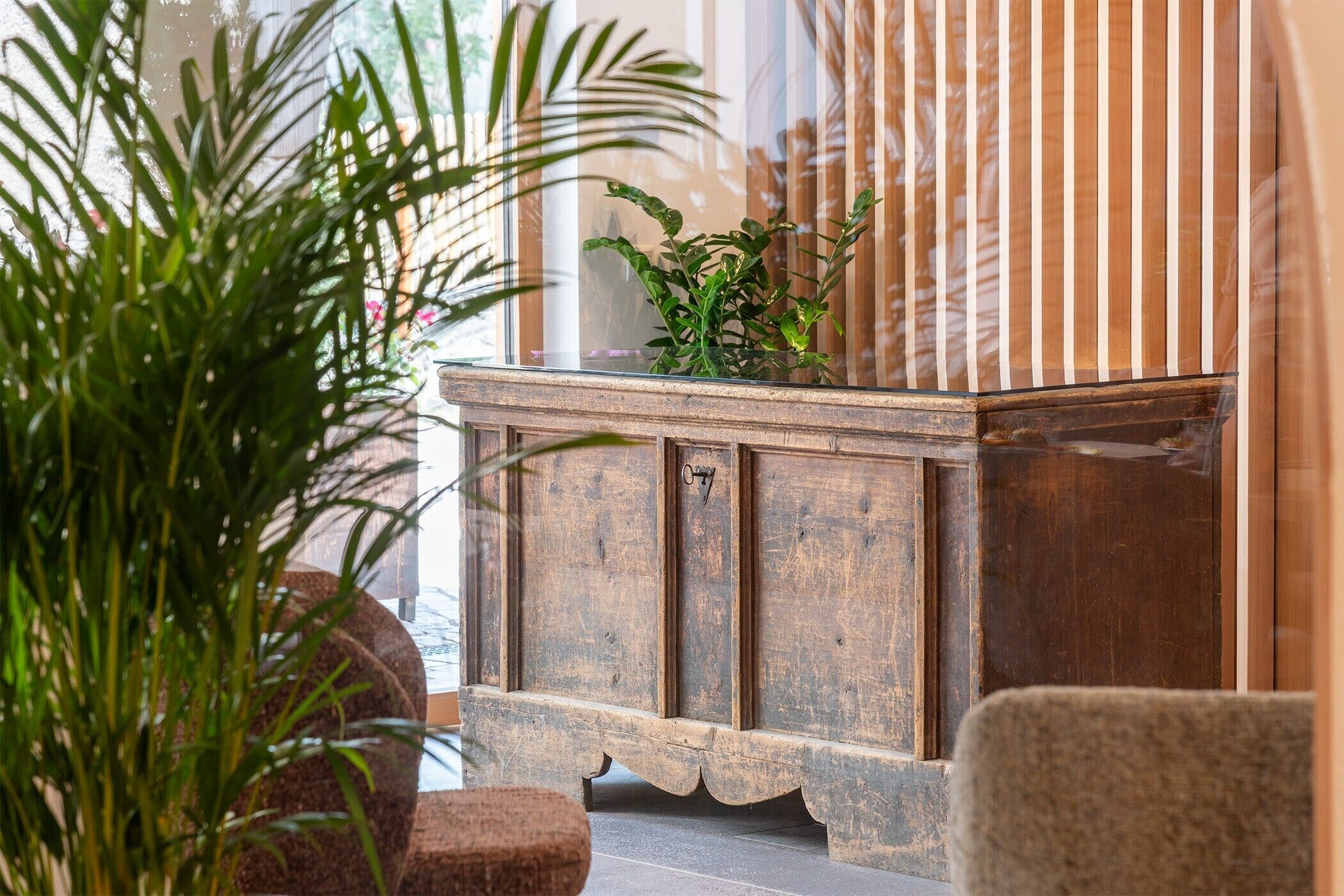 A wooden cabinet with a number '07' on it, placed in a room with a large window and a plant in front.