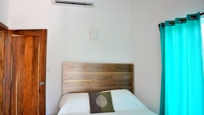 A bedroom with a wooden headboard, a bed with white bedding, a teal curtain, and a wooden door.