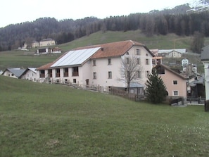 A large building with a sloped roof, surrounded by a fence and a grassy area. - Chasa Stella, (Ftan) by Interhome (Ftan)