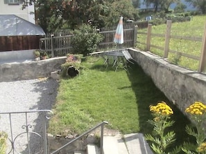 A residential outdoor area with a grassy lawn, a trampoline, and a small garden with yellow flowers. - Chasa Stella, (Ftan) by Interhome (Ftan)