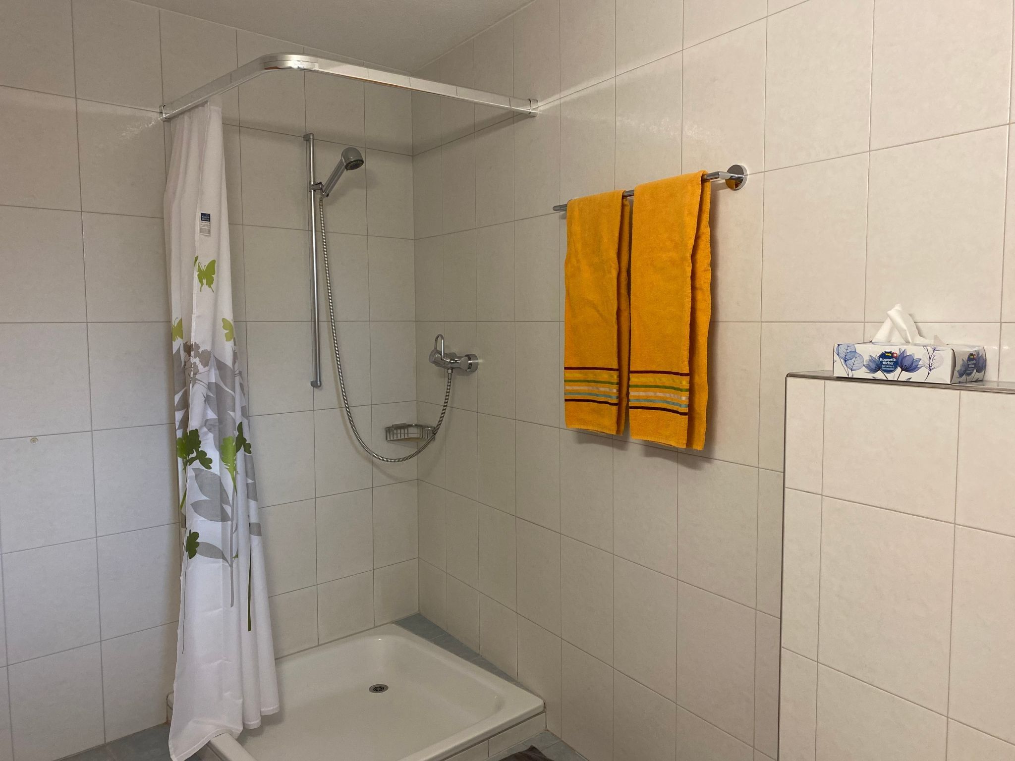 Ein Badezimmer mit Dusche, Toilette und einem Handtuchhalter mit einem gelben Handtuch.