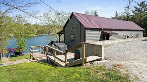 Une cabane avec un toit en métal, un quai et une vue sur un lac.