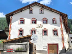 A traditional building with a sign for 'Hotel Alpena' and a terrace.