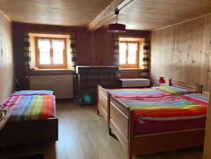 Ein Zimmer mit Holzboden, zwei Betten, einem Schreibtisch und einer Kommode.