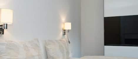 Ein Hotelzimmer mit einem Bett, zwei Wandlampen und einem großen Fenster.