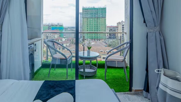 Een hotelkamer met balkon, een bed, een tafeltje, twee stoelen en uitzicht op de stad.