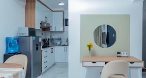 Eine moderne Küche mit weißen Schränken, einem Edelstahlkühlschrank und einem Wasserspender.