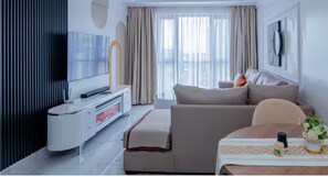 Ein modernes Wohnzimmer mit Sofa, Fernseher und einem Essbereich mit Tisch und Stühlen.