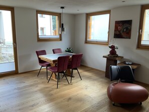 A dining area with a wooden table and chairs, a small side table with a vase, and a painting on the wall. - Chasa Siringia EG, (Samnaun-Laret) by Interhome (Samnaun)