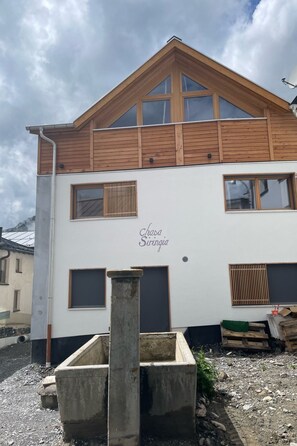 A two-story building with a sloped roof and multiple windows. - Chasa Siringia EG, (Samnaun-Laret) by Interhome (Samnaun)