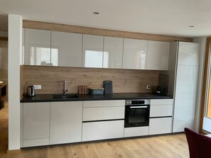 Een moderne keuken met witte kastjes, een zwart aanrechtblad en een inbouwoven.