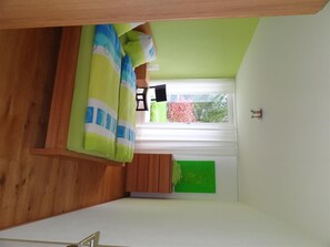 Una habitación compacta con cama, una mesita y una ventana con vistas a zonas verdes.