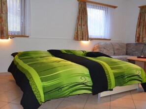 Ein Zimmer mit einem Bett, einer Couch und zwei Fenstern mit Vorhängen.