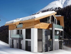 Un edificio moderno de varios pisos con fachada de madera, ventanas grandes y un balcón.