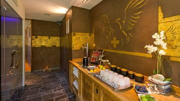 Eine Hotelhalle mit einer Rezeption, einer Kaffeestation und einer Wand mit goldenen Kunstwerken.