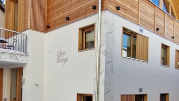 Ein modernes Gebäude mit weißer Fassade, Holzelementen und zahlreichen Fenstern.