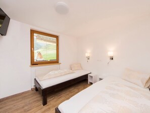 A bedroom with a bed, bedside tables, a window with a view, and wall-mounted lights. - Chasa Sulai, (Samnaun-Laret) by Interhome (Samnaun)