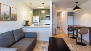 A modern kitchen with pendant lighting, a dining area with a table and chairs, and a living room with a sofa. - Evergreen Escape by Velo (Angel Fire)