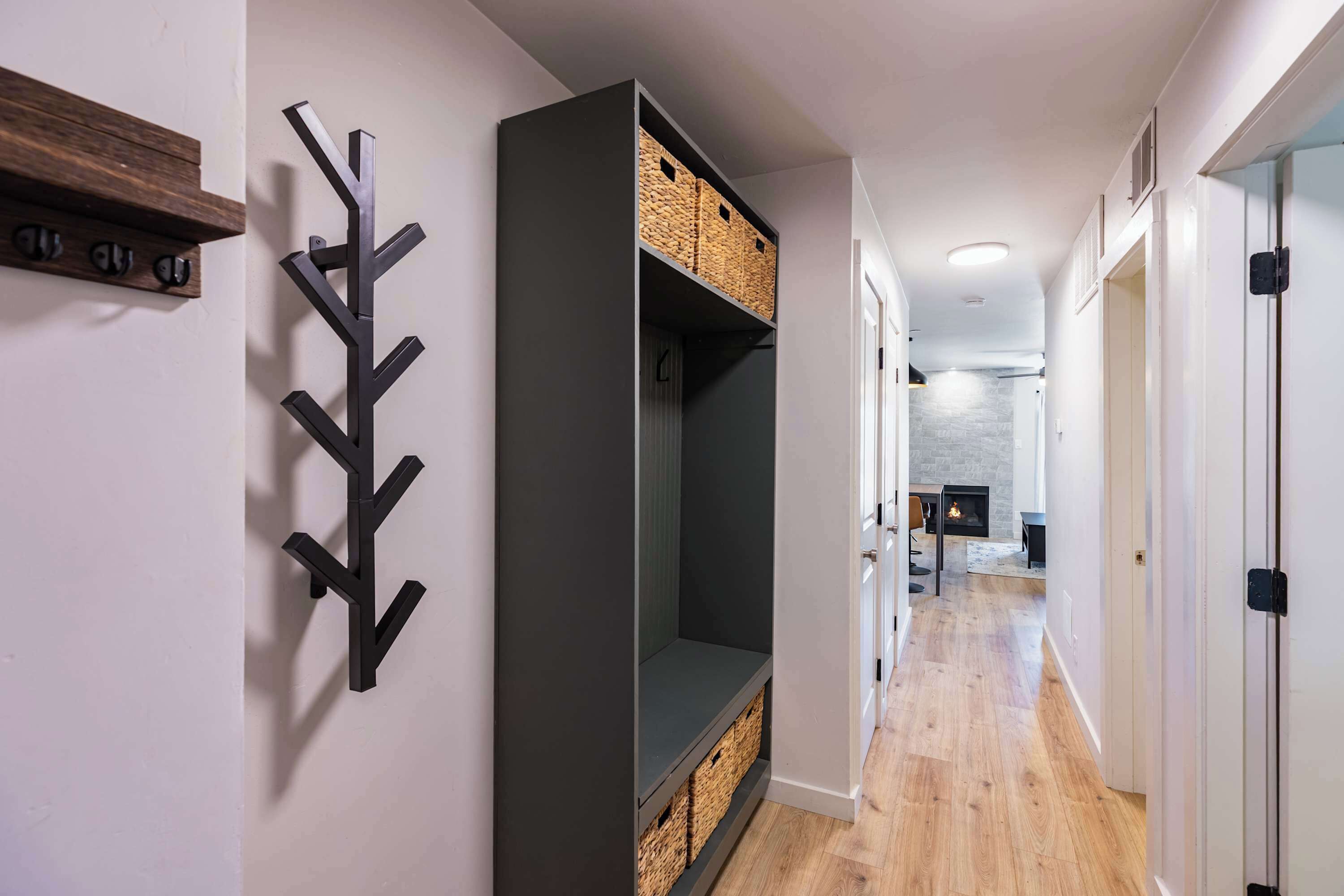 A hallway with a built-in bench, wall-mounted baskets, and a modern light fixture.