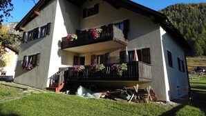 Un bâtiment à deux étages doté de balcons, d’un escalier et ayant une chaîne de montagnes en toile de fond.