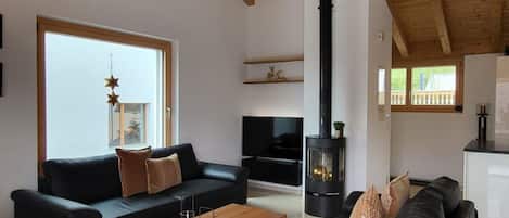 Een moderne woonkamer met een hoge plafond, een open haard en een groot raam.