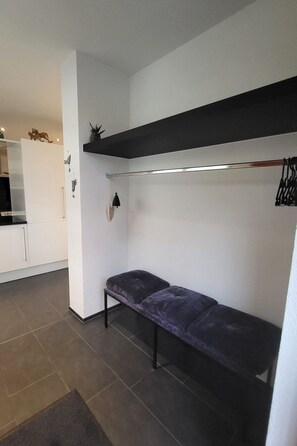 A compact room with a built-in bench, a small shelf, and a wall-mounted light fixture. - Chasa Scandella, (Sent) by Interhome (Sent)
