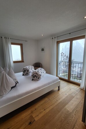 A bedroom with a bed, a window, and a balcony with a view. - Chasa Scandella, (Sent) by Interhome (Sent)
