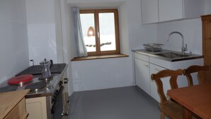 Una cocina pequeña con ventana, un lavamanos y electrodomésticos básicos.