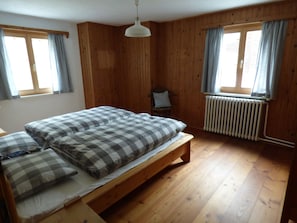 A room with a bed, a chair, wooden walls, and a radiator. - Somvi 56, (Tschlin) by Interhome (Tschlin)