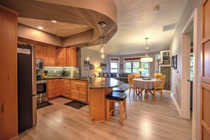 A modern kitchen with wooden cabinets, a stainless steel refrigerator, and a dining area with a table and chairs. - 3-bedroom condo on Red Cedar Lake, Tagalong Birchwood perfect for relaxing stays (Birchwood)