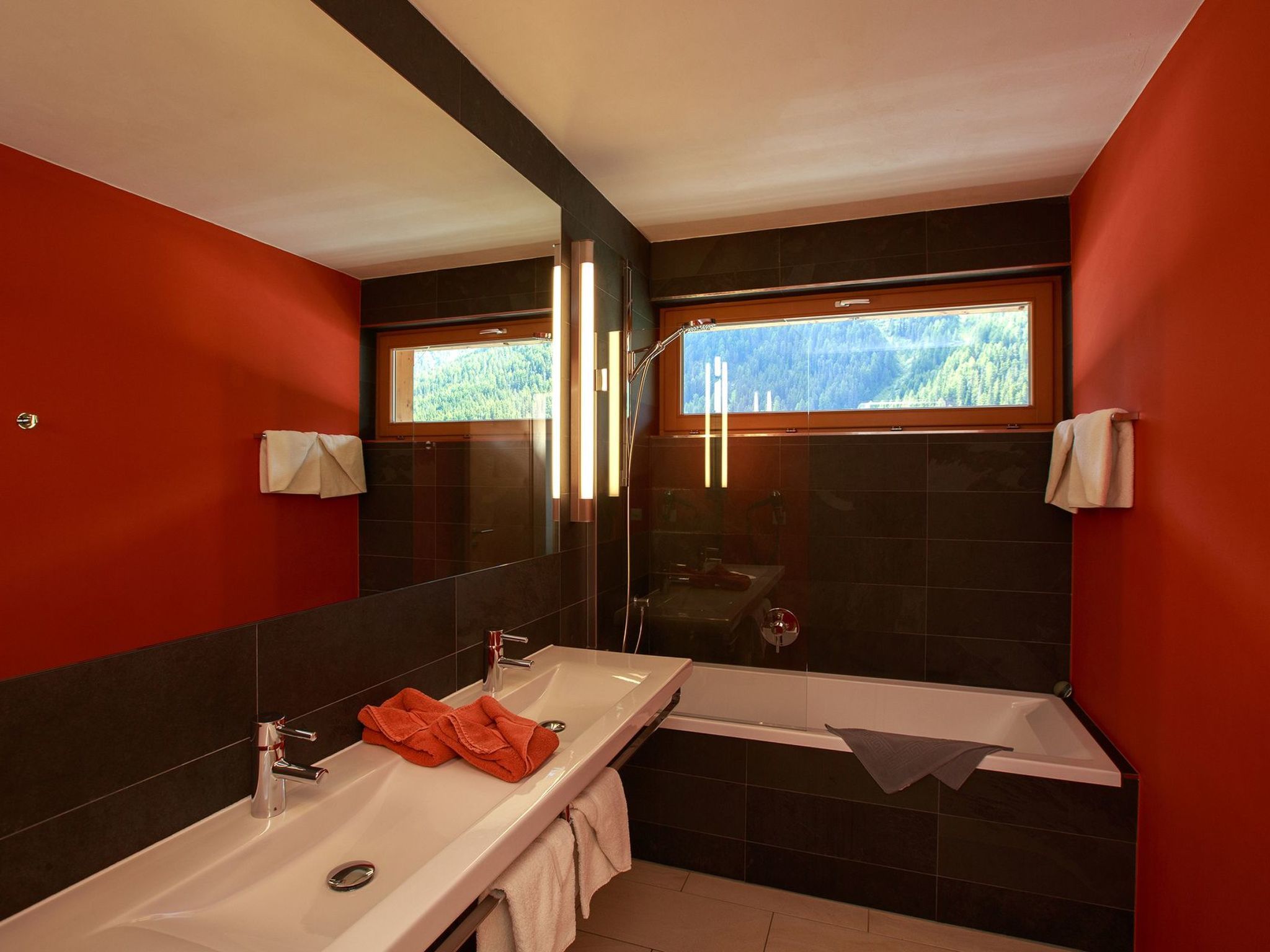 A modern bathroom with a large mirror, two sinks, a bathtub, and a shower.