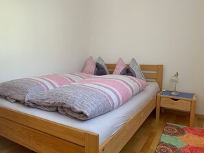 A single bed with a wooden frame, a bedside table with a lamp, and a patterned rug on the floor. - Sotchà 8c, (Scuol) by Interhome (Scuol)