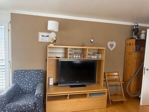 A living room with a flat-screen TV, wooden entertainment unit, and a sofa. - Sotchà 8c, (Scuol) by Interhome (Scuol)
