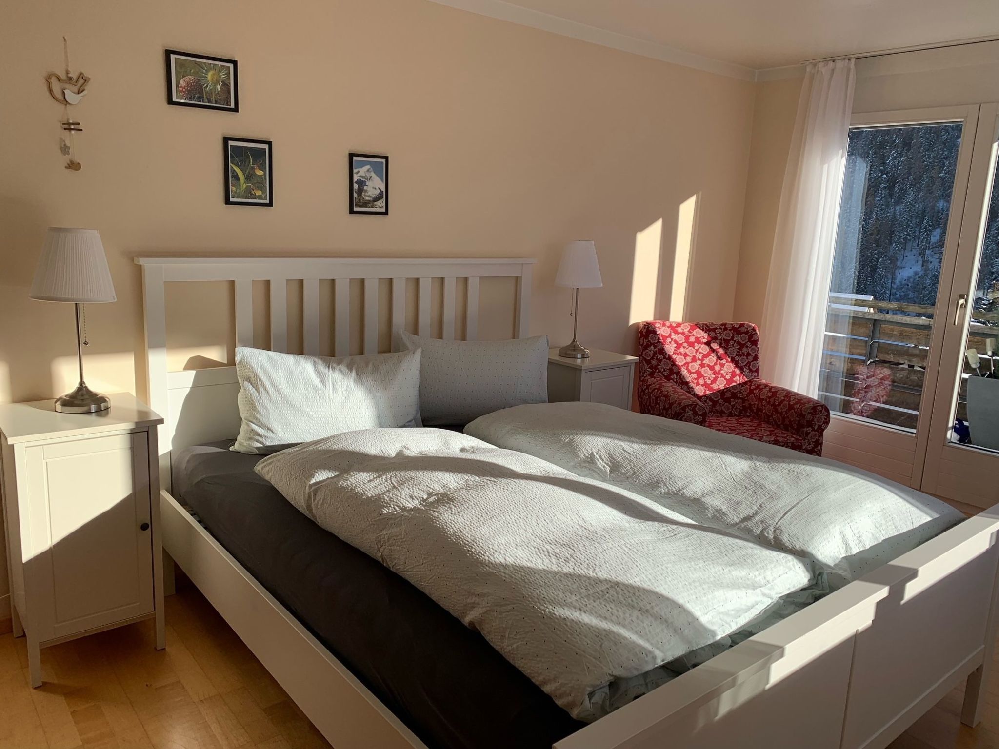 Un dormitorio con cama, mesitas de noche, una silla y una ventana con vistas.