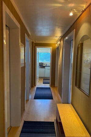 A hallway with a wooden bench, a kitchen visible through an open door, and a black mat on the floor. - Sotchà 8c, (Scuol) by Interhome (Scuol)