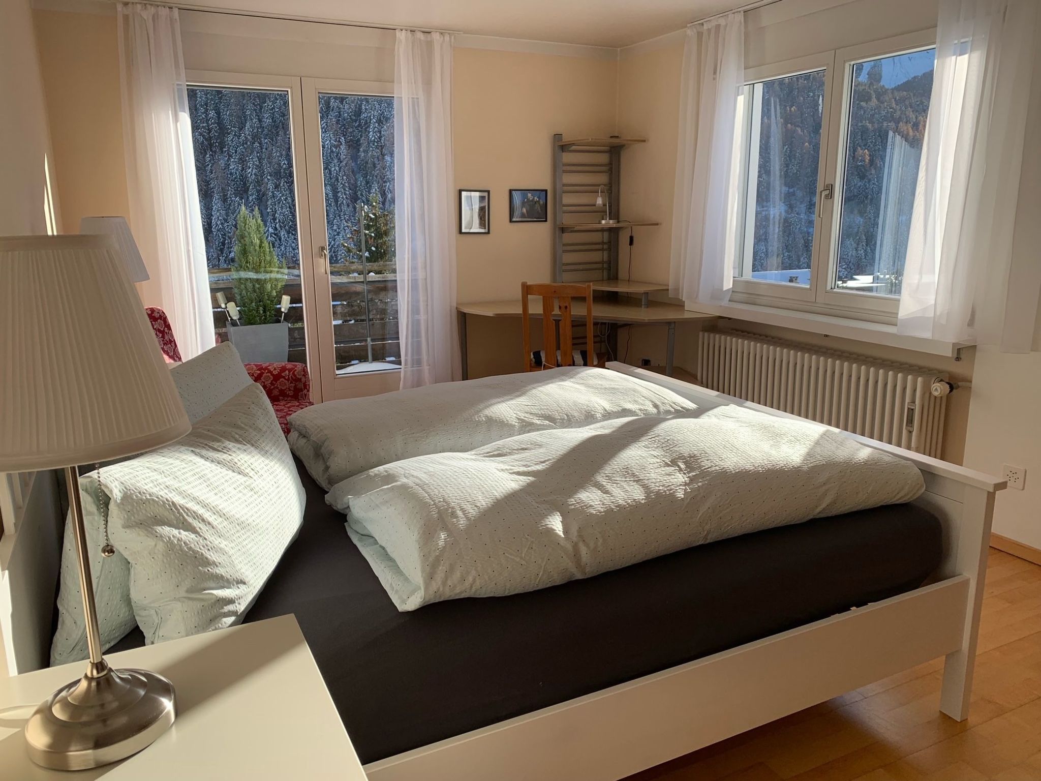 A bedroom with a bed, a desk, and a chair.