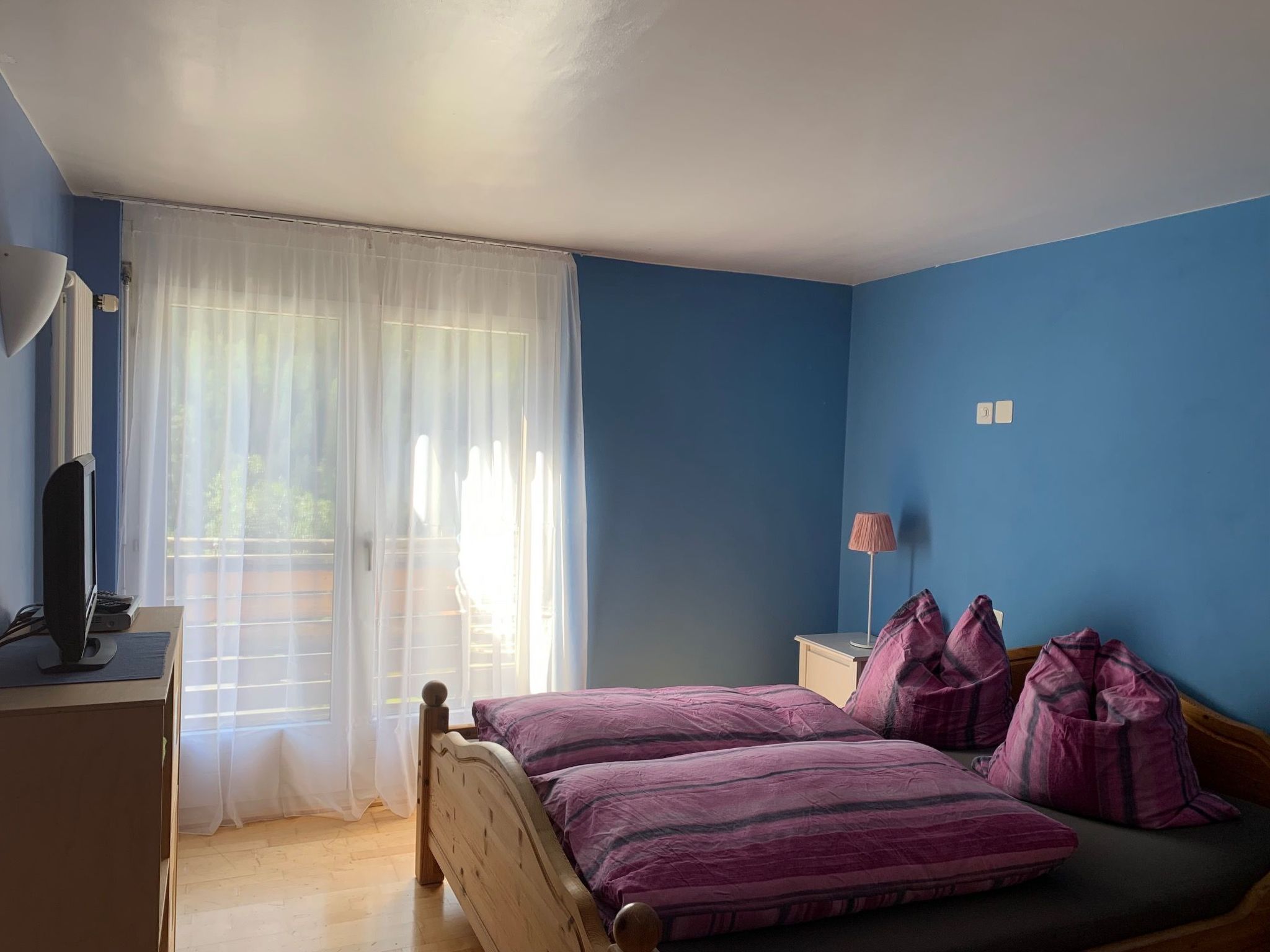 Een slaapkamer met een bed, een bureau en een lamp.