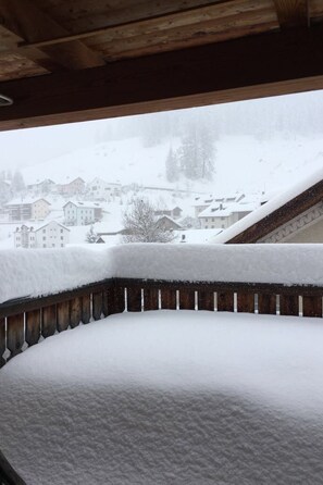 Ein mit Schnee bedeckter Balkon mit Blick auf eine Stadt und ein schneebedecktes Dach.