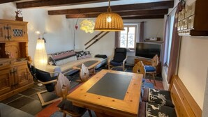 Una sala de estar acogedora con un sofá, sillones, una mesa, un televisor y un mueble de madera.