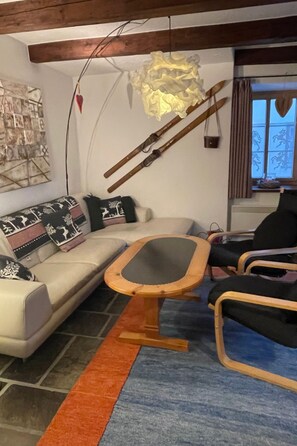 Ein Wohnzimmer mit einer Couch, einem Holztisch und einem gemusterten Teppich.