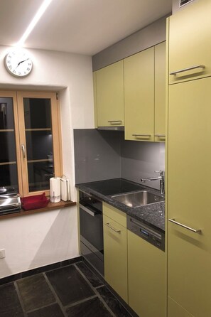 Une cuisine équipée d’une cuisinière intégrée, d’un évier et d’une fenêtre à cadre en bois.