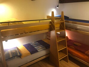 Ein Schlafraum mit Etagenbett, einer Leiter, einem Schreibtisch und einem Stuhl.