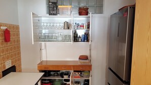 Een keuken met een inbouwkastenwand, een koelkast en een eettafel.