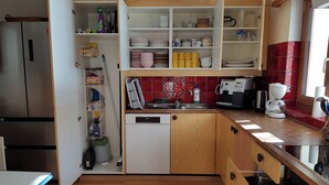 Een keuken met houten kastjes, een vaatwasser, een koffiezetapparaat en een backsplash met rode tegels.