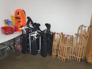A storage area with various items including a red container, black and white bicycles, and wooden crutches. - Ferienhaus Plaun Grond, (Tschierv) by Interhome (Tschierv)