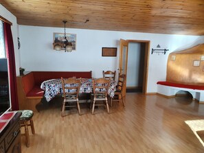 A dining area with a wooden table and chairs, a bench, and a ceiling fan. - Ferienhaus Plaun Grond, (Tschierv) by Interhome (Tschierv)